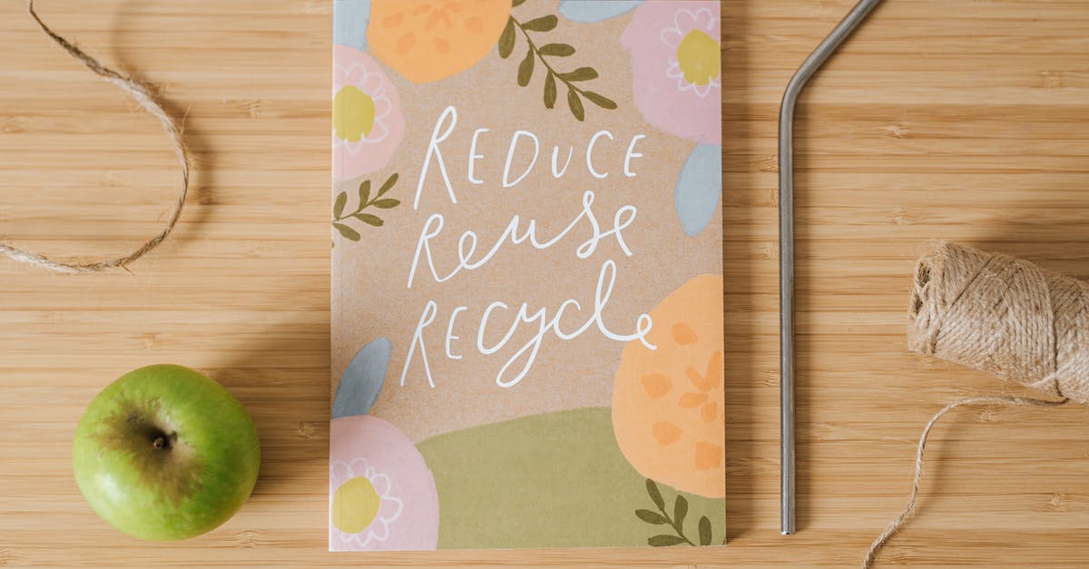 How to reduce scandal? - Top view of book with Reduce Reuse Recycle inscriptions near green apple and bobbin of thread on table How to reduce scandal? - Top view of book with Reduce Reuse Recycle inscriptions near green apple and bobbin of thread on table
