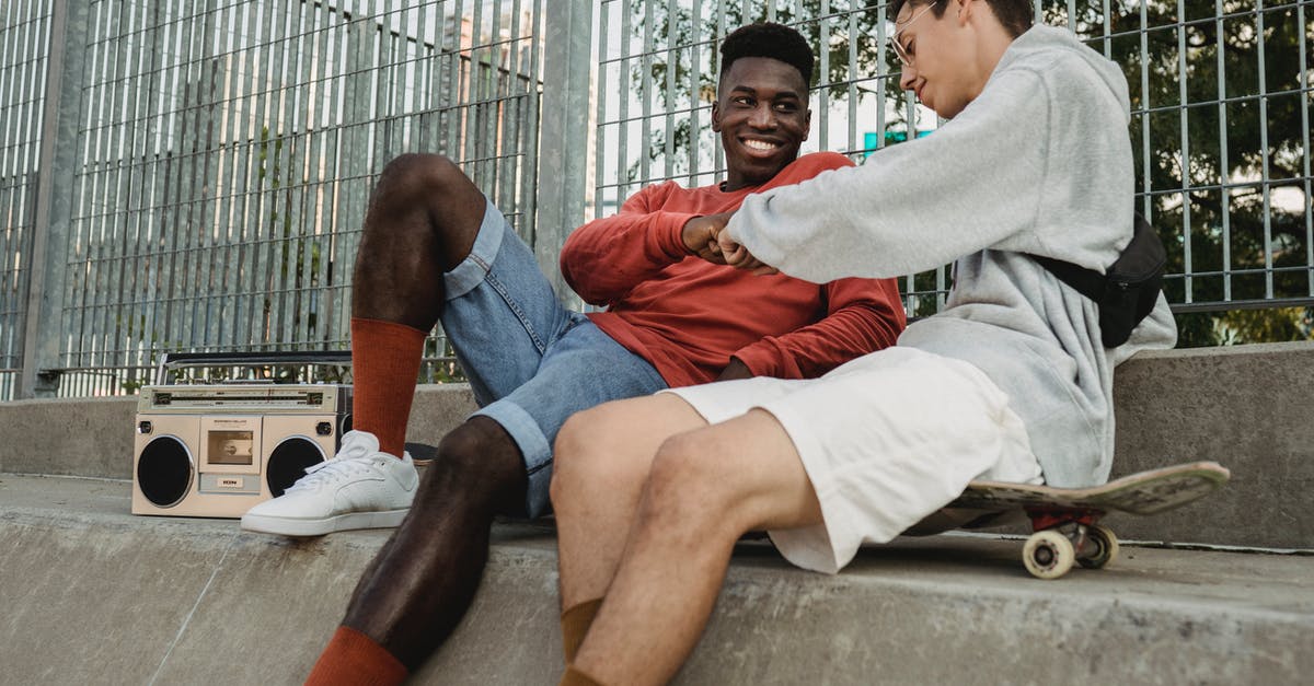 How to remove a real-id from a friend in BattleNet? - From below of smiling black guy with retro tape recorder fist bumping with male friend sitting on skateboard while chilling on concrete basement of metal railing