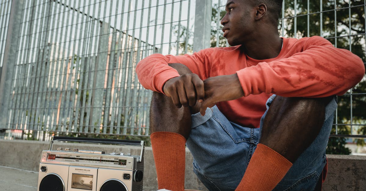 How to replace the in-game music in Asphalt 8: Airborne? - Stylish young African American guy listening to favorite song on retro cassette recorder while sitting on skateboard and looking away on summer day