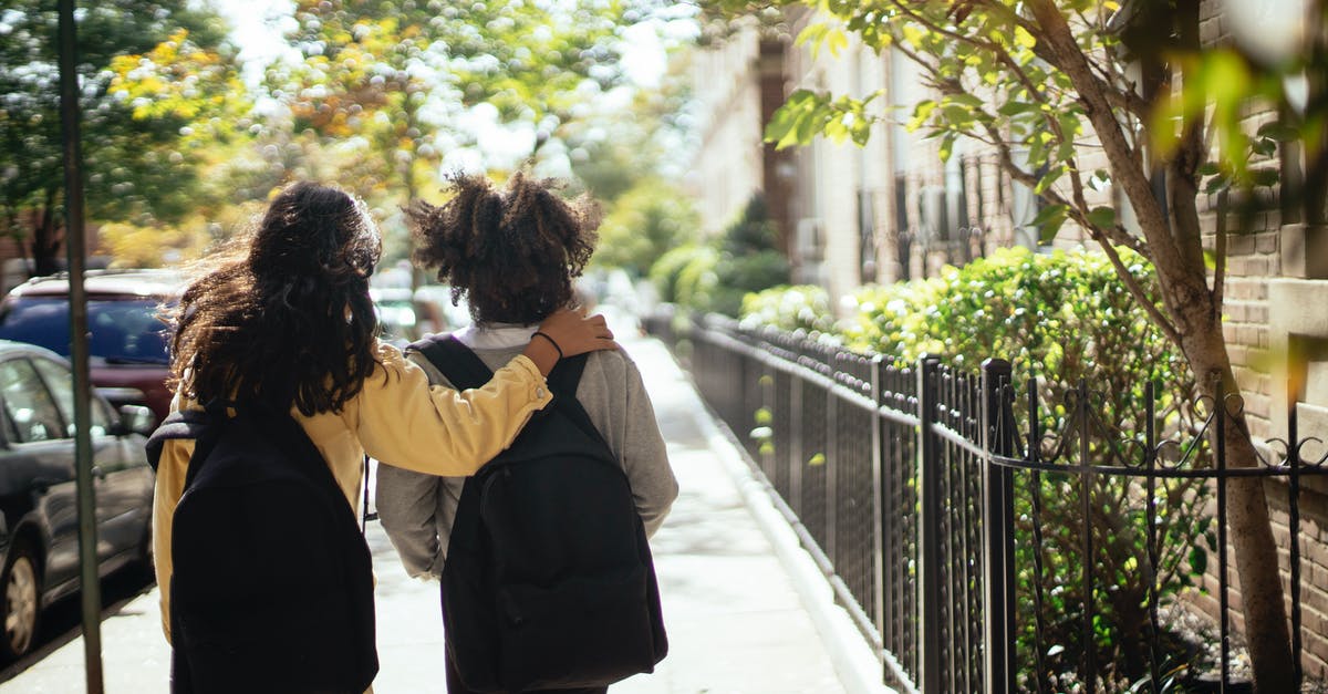 How to return to a visited city? - Back view of unrecognizable girls walking together along street while returning home from school How to return to a visited city? - Back view of unrecognizable girls walking together along street while returning home from school