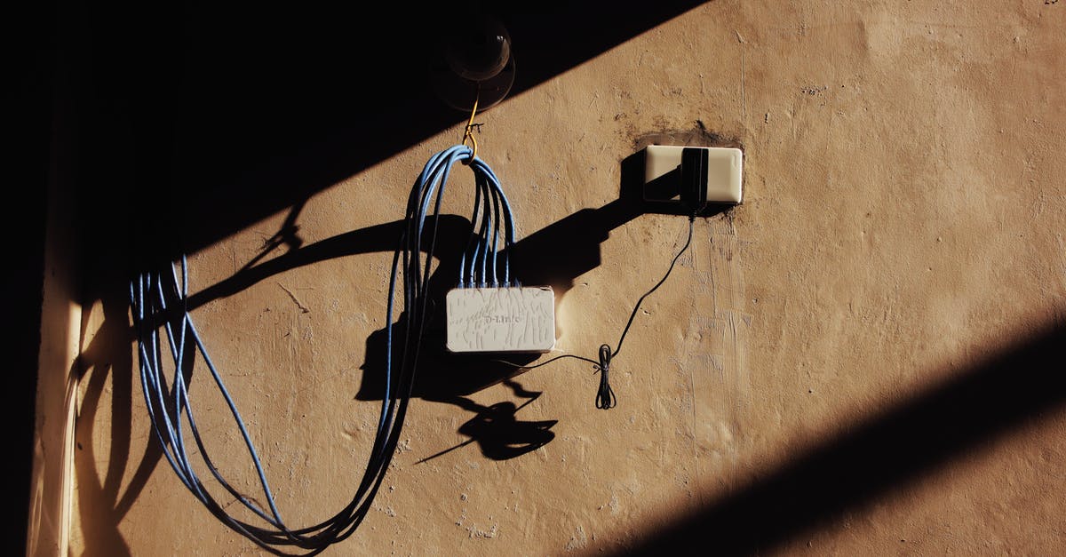 How to specify the network adapter for my cstrike 1.6 dedicated server? - Electric blue wires connected to network adapter plugged in socket on shabby brown wall of building on street with shadow