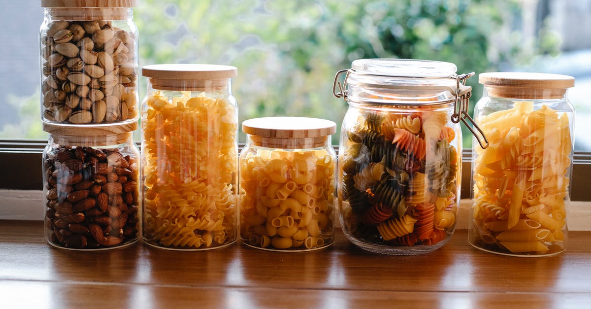 How to stack runes of same type? - Glass jars filled with assorted types of uncooked pasta and pistachios with almonds placed on wooden table near window in light room