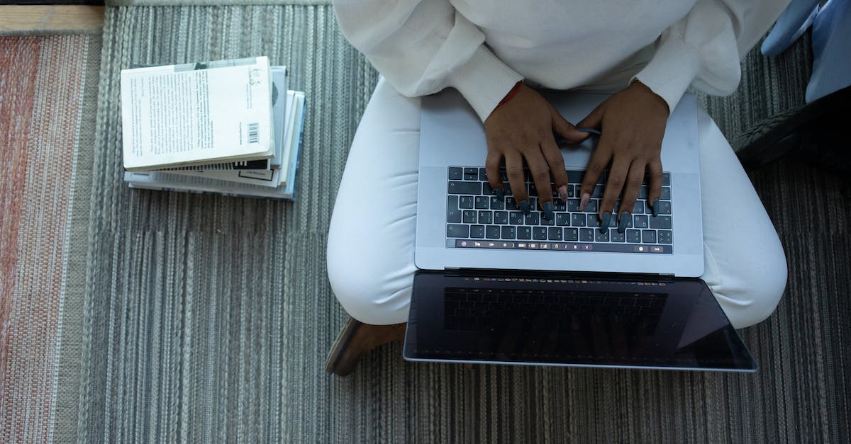 How to stack runes of same type? - Top view of anonymous African American female student sitting with crossed legs and typing on netbook sitting near stack of books