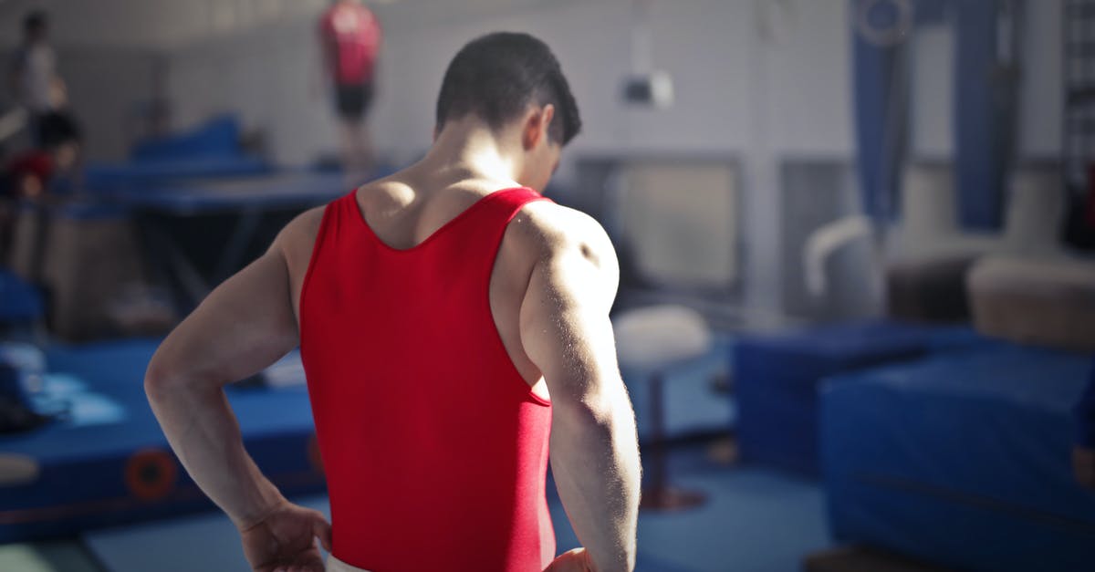 How to start with the most Health? - Back view of muscular athlete in red uniform preparing for training in gymnast hall with equipment