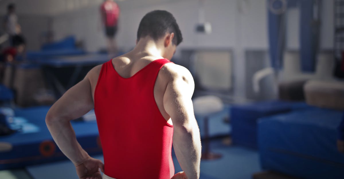 How to start with the most Health? - Back view of muscular athlete in red uniform preparing for training in gymnast hall with equipment How to start with the most Health? - Back view of muscular athlete in red uniform preparing for training in gymnast hall with equipment