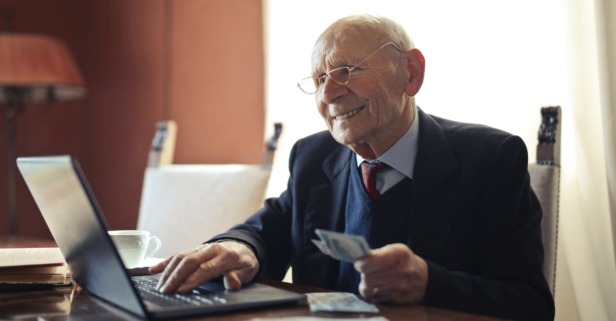 How to successfully cross a river without using money - Positive senior businessman typing on laptop while holding money in hand