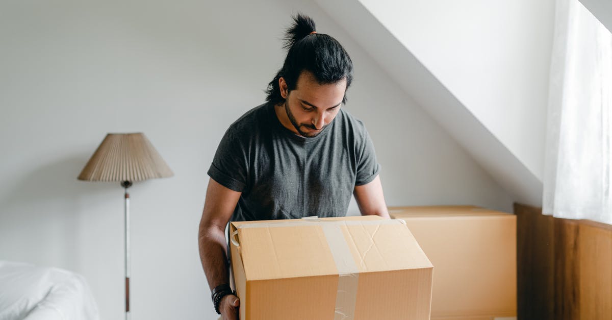 How to take screenshots of the old games - Ethnic guy picking up cardboard box in house How to take screenshots of the old games - Ethnic guy picking up cardboard box in house