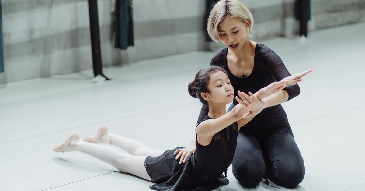How to teach my child my profession in the guild 2? - Ethnic female ballet dancer supporting flexible child during training on floor in dancing hall