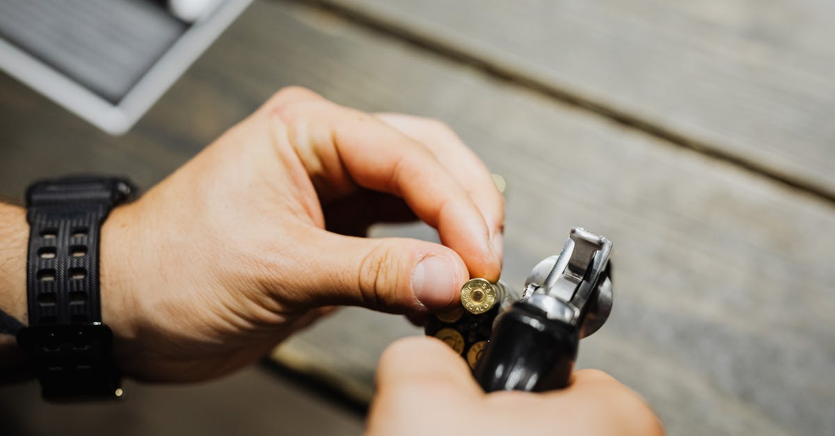 How to tell if a weapon is one or two-handed - Hands of a Person Holding a Gold Bullet and a Pistol