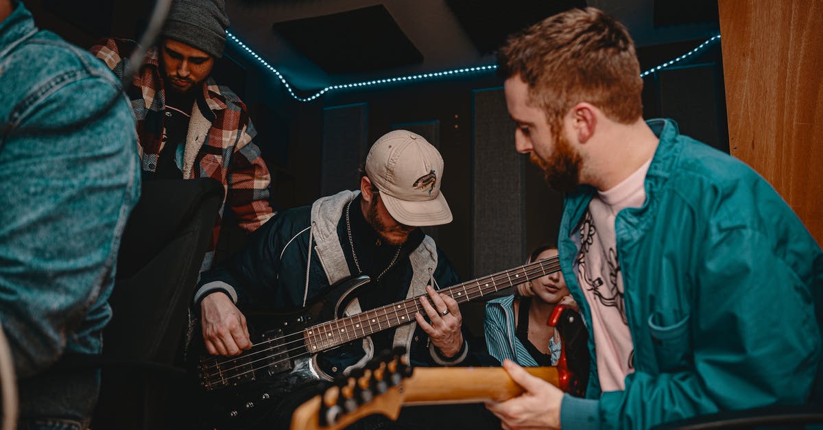 How to tell which party members a skill affects - Young men in warm clothing playing electric guitar at party in small room decorated with blue garlands