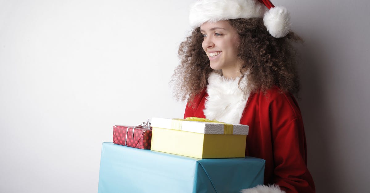 How to unlock content in Magic Origins - Side view of cheerful female with curly hair wearing Santa hat and costume standing with stack of wrapped presents on white background in studio and looking away How to unlock content in Magic Origins - Side view of cheerful female with curly hair wearing Santa hat and costume standing with stack of wrapped presents on white background in studio and looking away