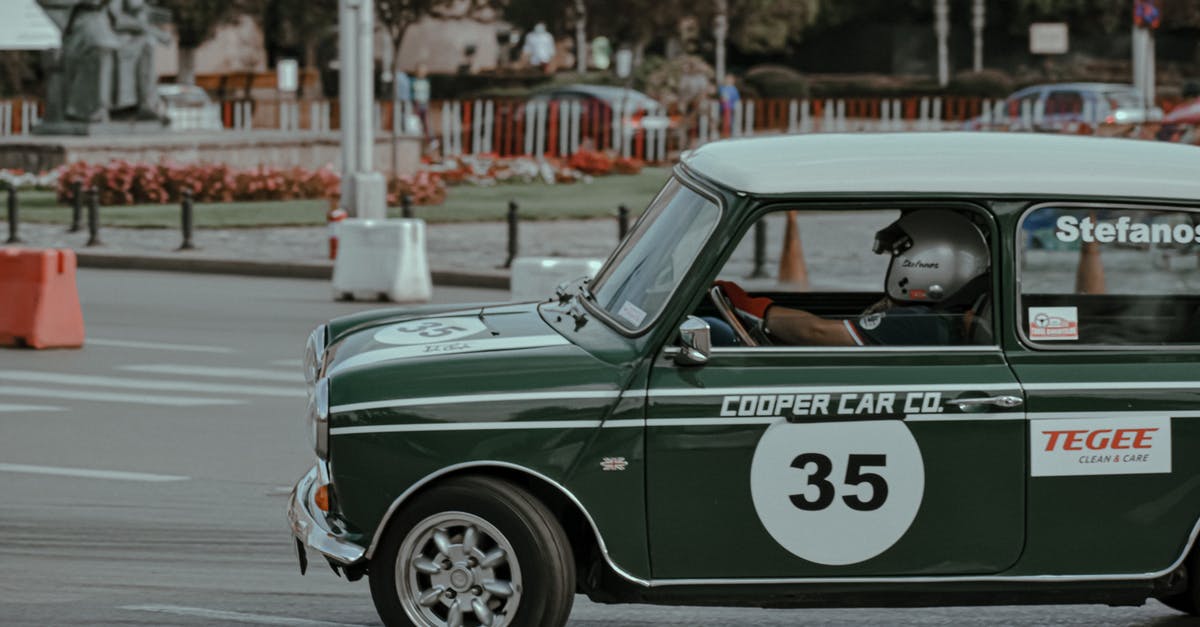 How to use a switch to turn a timer on without the timer turning itself off? - Small green vintage car with driver in helmet on asphalt street during rally