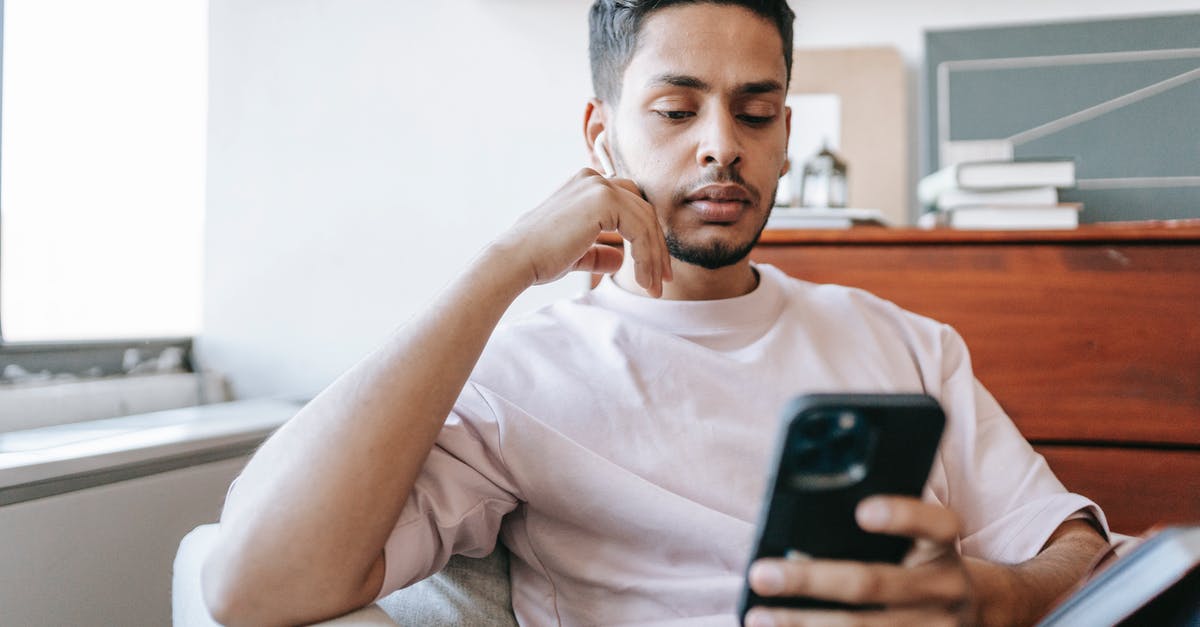 How to use multiplayer over Bluetooth - Thoughtful Indian man with wireless earbuds messaging on smartphone