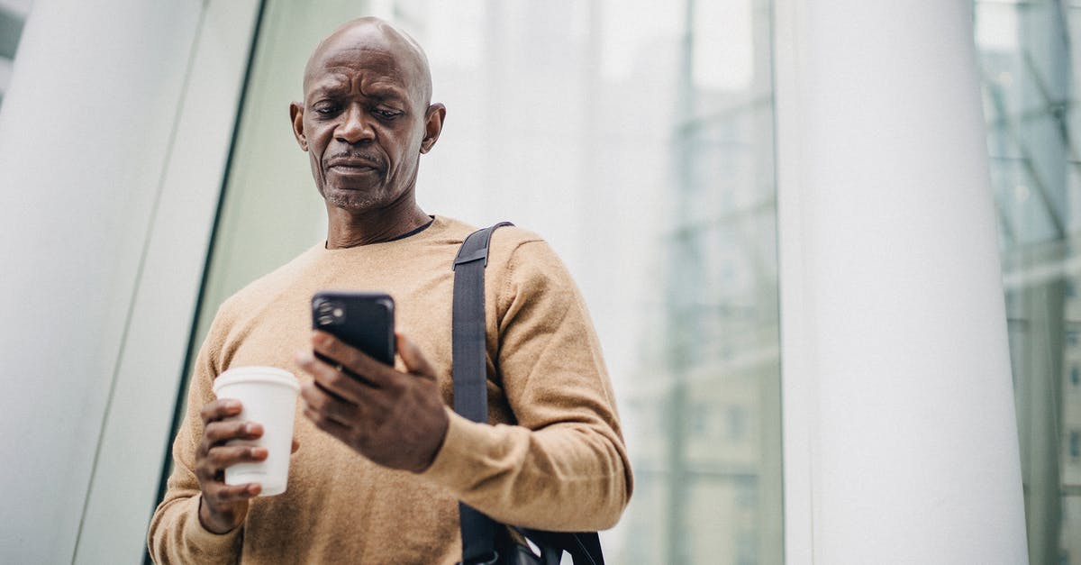 How to use the 'Free from captvity' option from the intrigue focus - Focused mature black man chatting on smartphone during coffee break on street