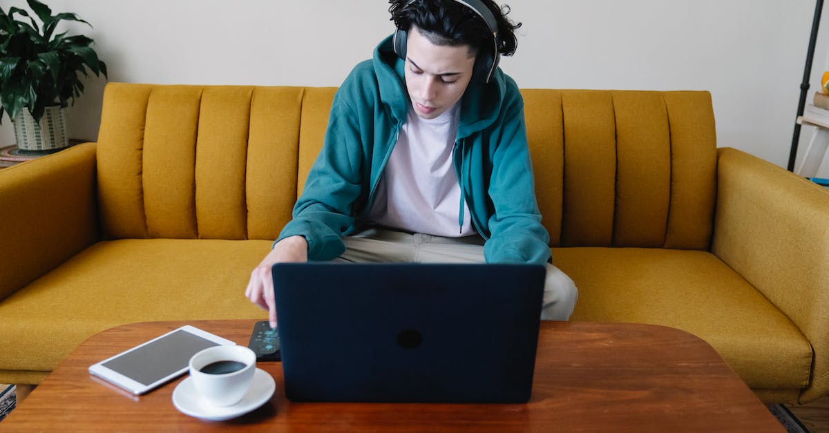 How to use the 'Free from captvity' option from the intrigue focus - High angle of busy young male in headphones sitting on sofa and using cellphone at table with netbook coffee and tablet
