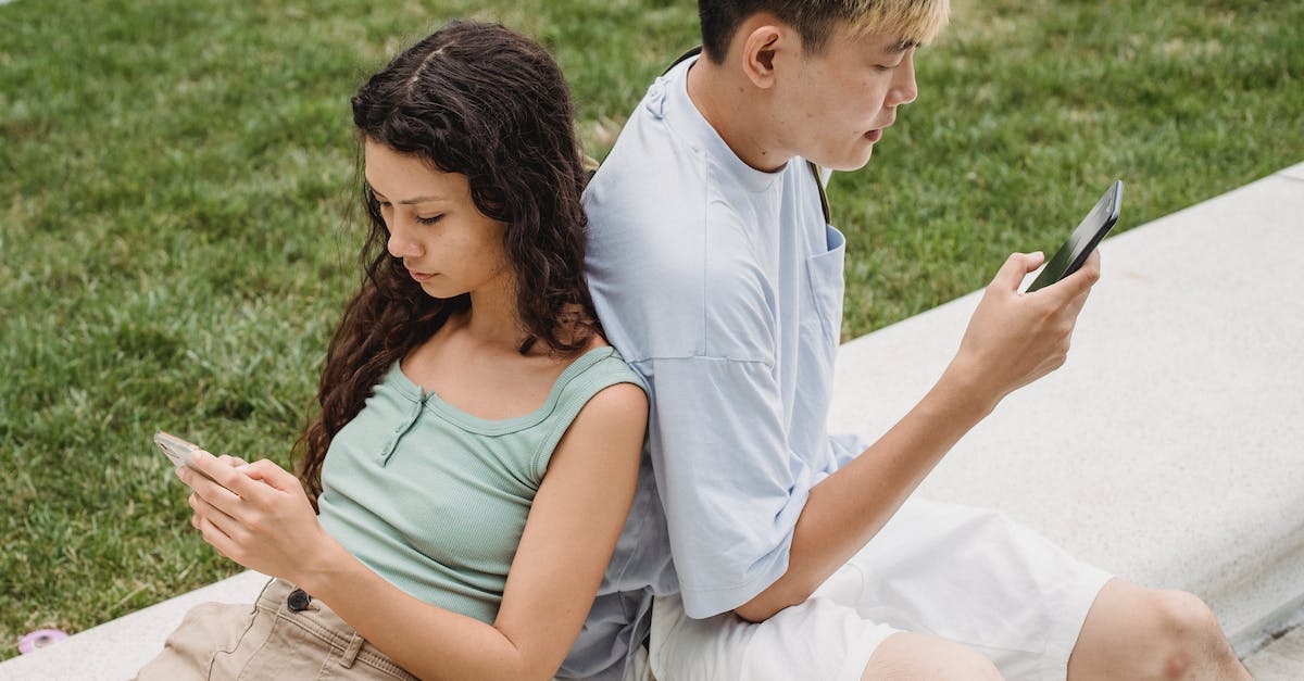 How to use the 'Free from captvity' option from the intrigue focus - From above of crop diverse couple text messaging on cellphones while sitting on bench near lawn in daylight