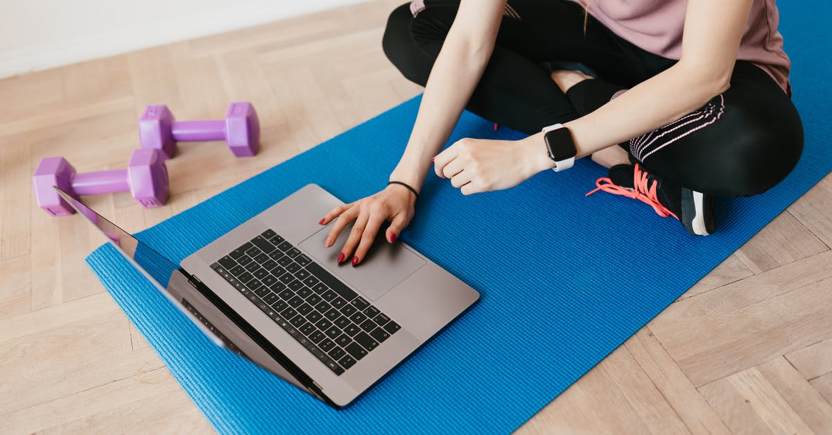 How to use the Active Life Mat with a Wii Mini? - Crop female in sportswear sitting on blue yoga mat on floor and surfing internet on laptop