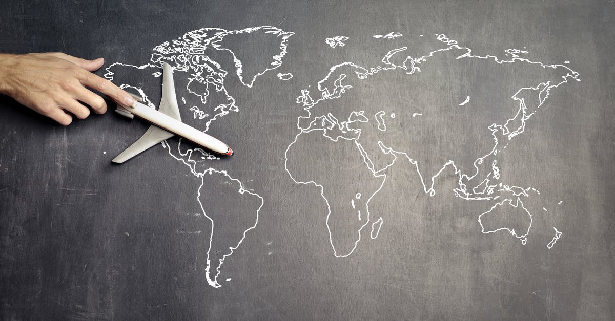 How to view map of the world - From above of crop anonymous person driving toy airplane on empty world map drawn on blackboard representing travel concept