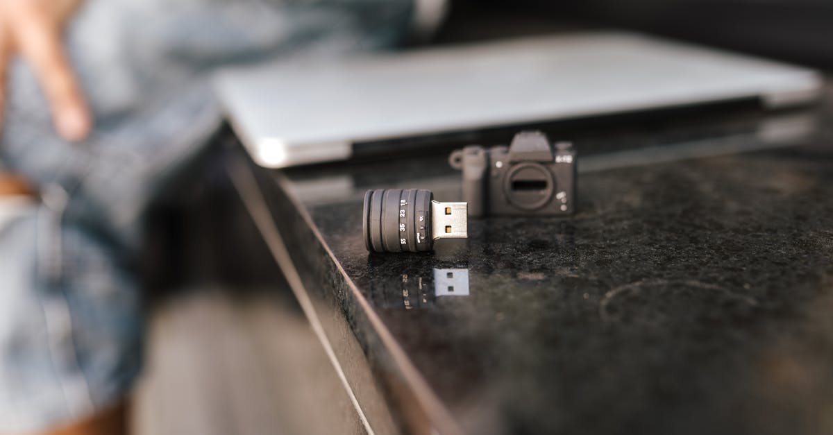 How were Memory Cards connected to the Original Xbox? - Crop anonymous male sitting on stone bench with modern netbook and portable contemporary USB adapter