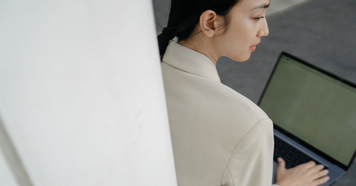 How would I be able to keep a mob a certain distance away in a specific direction from the player? - From above of crop concentrated young Asian female freelancer with long dark hair in elegant outfit working remotely on laptop while sitting on bench on street
