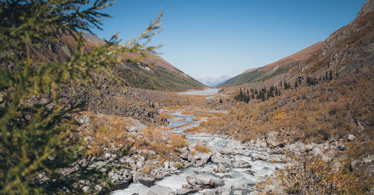 Hydro Plant not allowing water flow through - River flowing through mountainous terrain under blue sky Hydro Plant not allowing water flow through - River flowing through mountainous terrain under blue sky