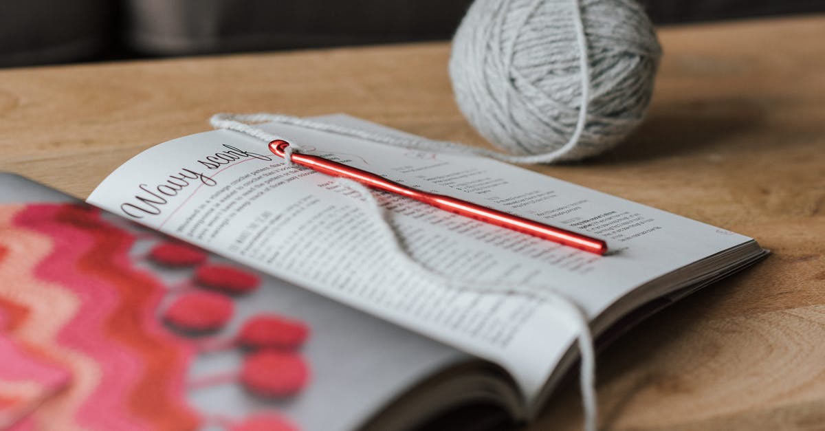 I've read an Auger recipe but I still can't craft one. Why? - Spherical gray ball of thread and red crochet needle with magazine on beige wooden table in daytime on blurred background