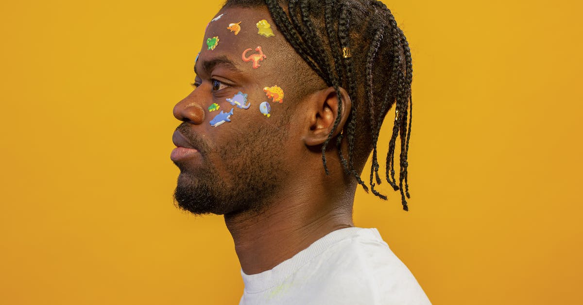 I can't get the Borderlands 2 profile editor to reduce Badass Rewards? - Side view of serious young bearded African American male millennial with braids and colorful stickers on face looking away against yellow background
