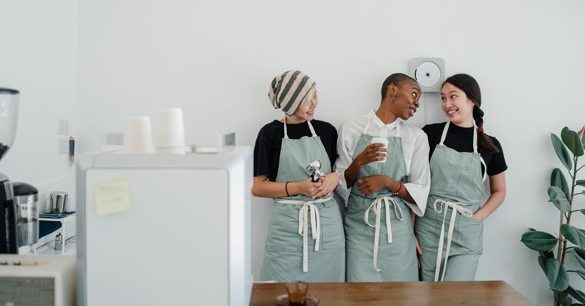 I can't see myself chat in Team Fortress 2 - Positive young multiethnic female baristas in aprons talking and smiling while working in modern light cafeteria