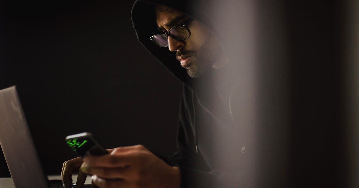 I can't use my Ember attack with Fennekin - Crop ethnic hacker with smartphone typing on laptop in darkness