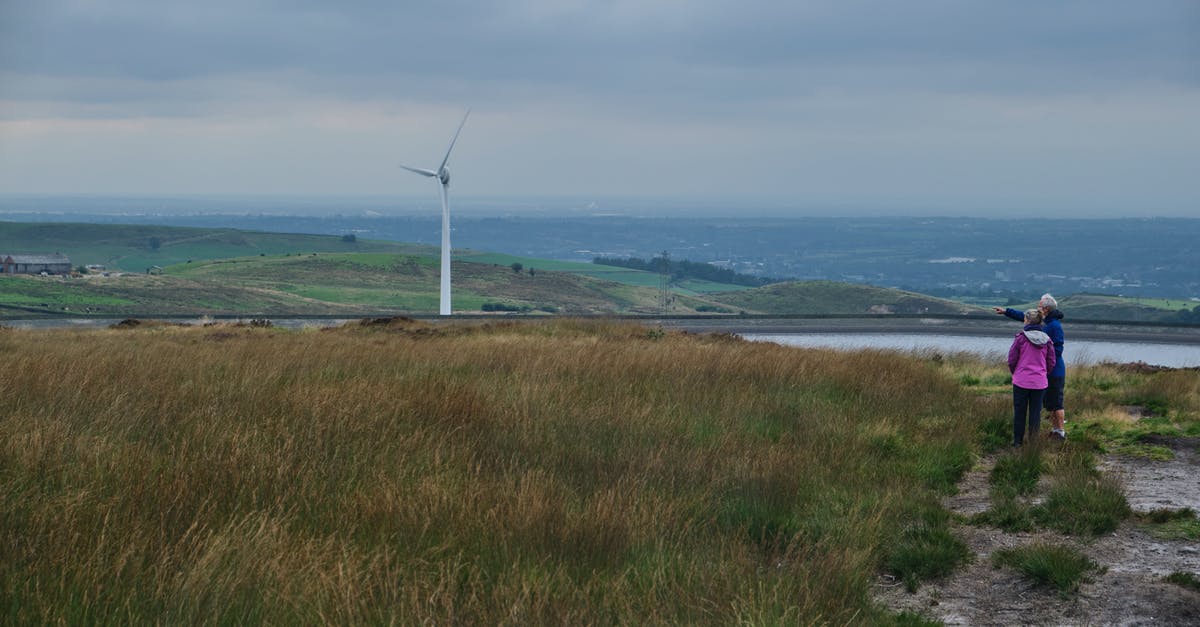 I need energy, which is better to upgrade, Hydro Plant or Solar Farm? - Anonymous female travelers looking at windmill in meadow in countryside
