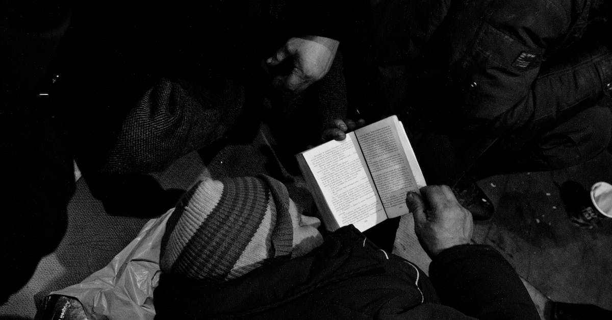 I need help with /execute - Black and white of homeless man lying on floor and reading book in night shelter for homeless