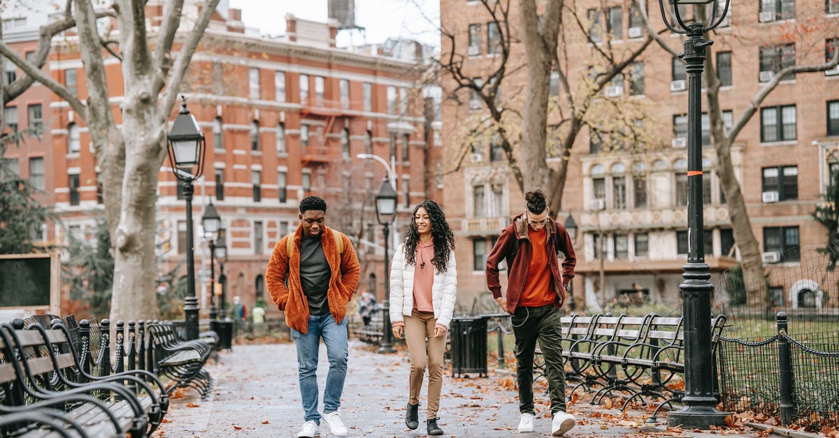 Identify relationship building dialog? - Full length of young positive multiracial friends in casual clothes walking in city park after studies on autumn day