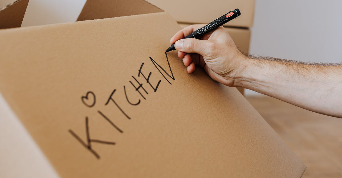Identify what replacement DVD module to purchase - Crop unrecognizable male using marker to write on carton box word kitchen and draw cute heart while packing kitchenware before relocation