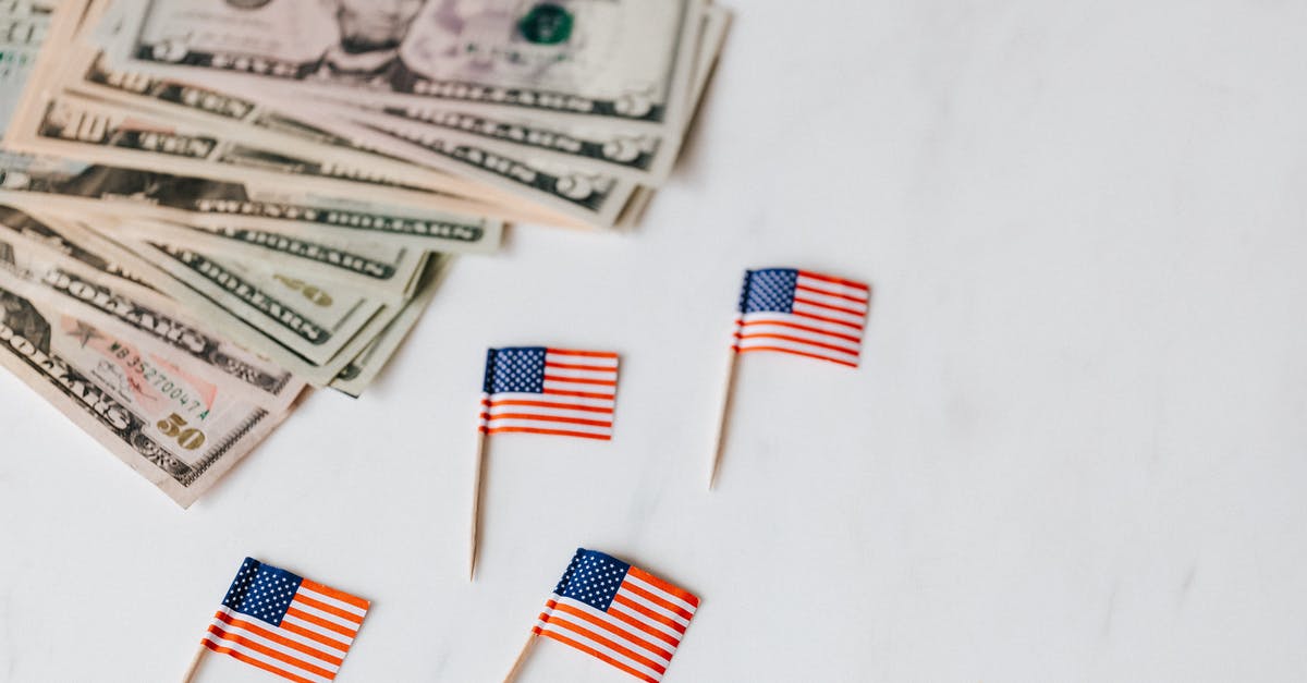 If I sign in to Humble Bundle monthly now, will I get this month's bundle or the next month's bundle? - From above of flags of United States of America on toothpicks placed near bundle of American dollars of different nominal pars on white surface of table
