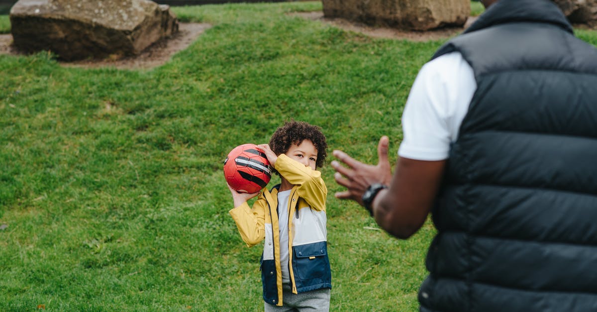 If you throw a red shell in first place, where does it go? - Content African American kid playing with red ball with unrecognizable black father while spending time in grassy park during weekend