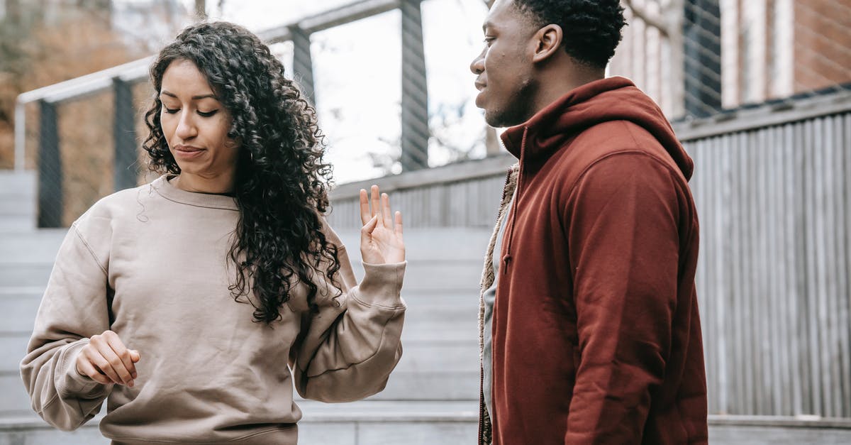 Ignored testfor parameters - Upset ethnic girlfriend with raised hand and concerned African American boyfriend breaking up on street against metal grid on background Ignored testfor parameters - Upset ethnic girlfriend with raised hand and concerned African American boyfriend breaking up on street against metal grid on background