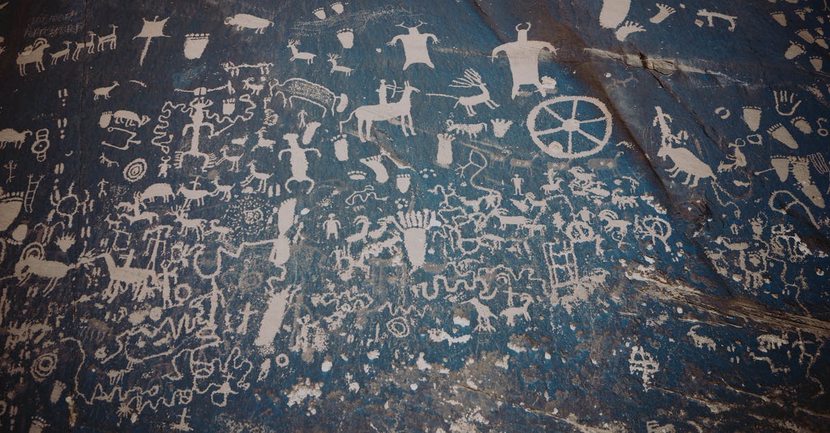 In BOTW where are the locations of all of the zora stone monuments - Newspaper rock with ancient symbols and petroglyphs with white paint on shabby stone blue wall with uneven surface in national park