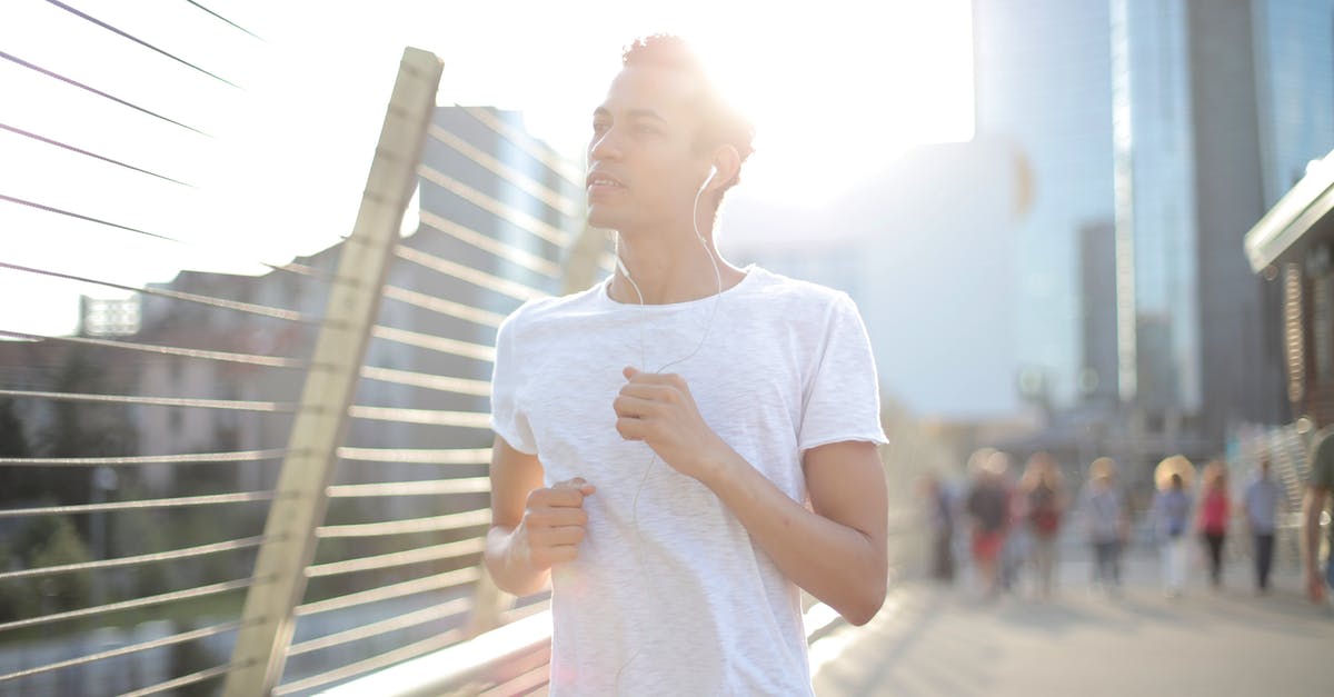 In the korok forest, why do the koroks run away from me when I get in their sight? - From below calm young African American sportsman in earphones and sportswear looking away with interest and contemplating while running alone along street and listening to music against blurred urban environment