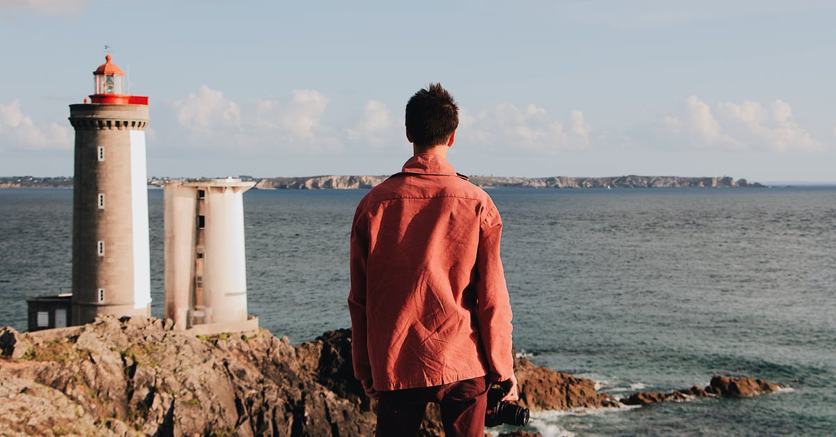 In the last sector 'The last stand', how to identify potential rebels location takeover? - Back view of unrecognizable male traveler in casual red clothes contemplating seascape while standing on rocky shore with lighthouse near rippling sea