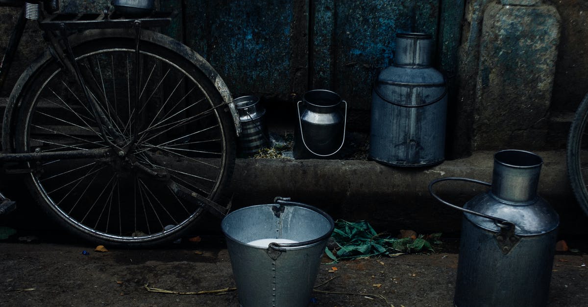 In which locations can I mine the most iron ore? - Tin vessels and metal bucket with milk placed near bike leaned on shabby rusty wall