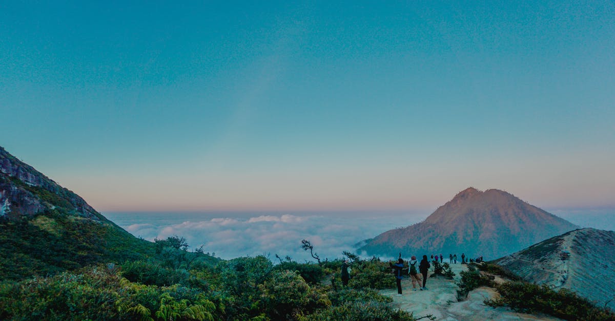 Increase cell loading range with distant landscape rendering off - Unrecognizable distant travelers admiring view of picturesque landscape of mountain range with green trees during  sunset