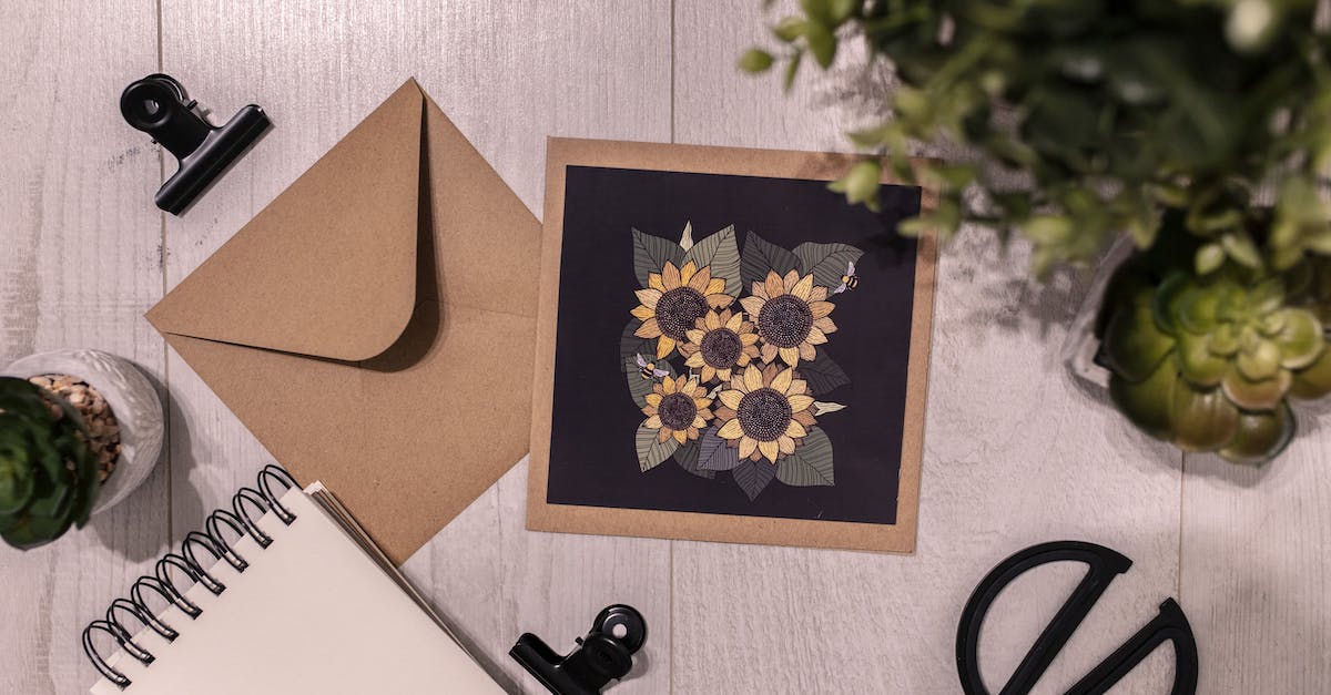 Inserting items into Writing Desk - Postcard and notebook on table near green plant