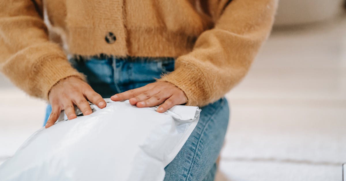 International(Uncut) version of Wolfenstein The New Order in Switzerland? - Crop faceless woman in casual clothes sitting on carpet while wrapping parcel bag for shipping in light room