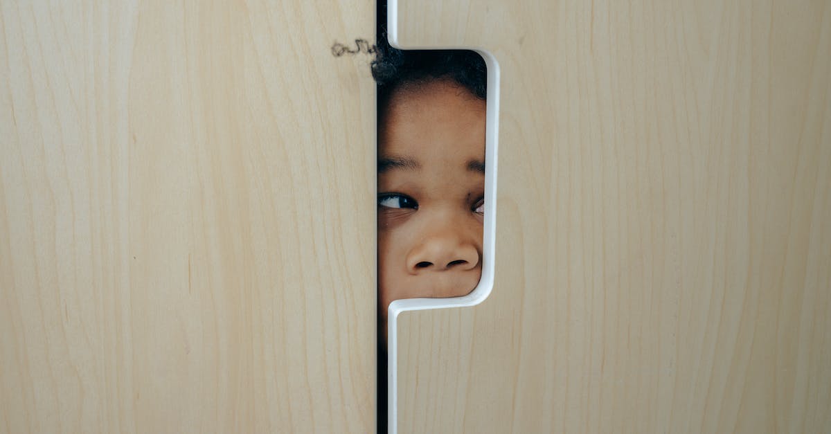 Is Black Hole a Knockback? - Anonymous funny little ethnic child hiding in wardrobe and peeping through hole while playing at home