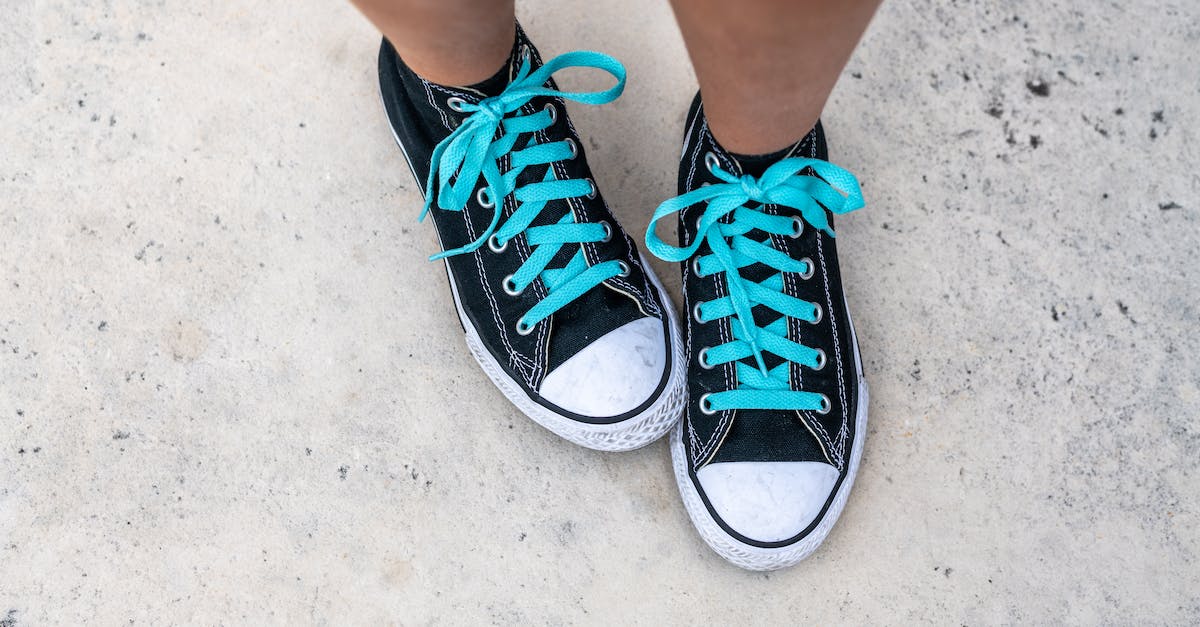 Is Black Hole a Knockback? - Top view of crop anonymous person in trendy footwear with blue shoelaces on gray background in daytime