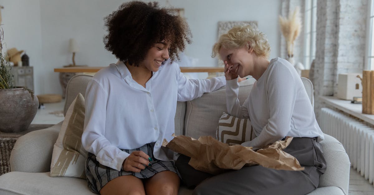 Is chat available to Xbox Live Free? - Happy young multiethnic female friends in casual clothes laughing while relaxing on comfortable couch and gossiping together at home