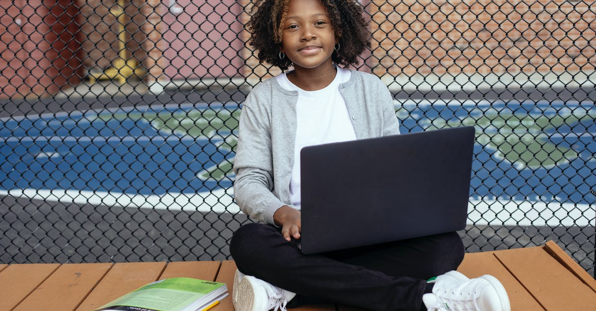 Is Clash cross platform multiplayer without account transfer? - Smiling African American schoolchild with Afro hairstyle sitting with netbook on crossed legs while studying and looking at camera near grid fence