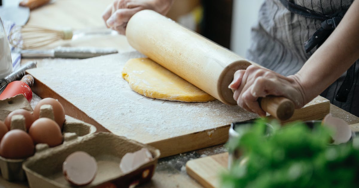 Is it possible make the pod reach inside the Hangar 21? - Unrecognizable female cook flattening dough with rolling pin while standing at table with wooden board against blurred background in kitchen