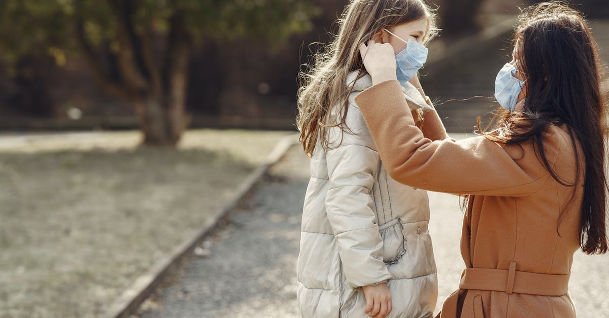 Is it possible to adjust your walk speed? - Side view of mother in outerwear and mask standing near cute daughter in warm wear looking at each other adjusting mask on face in autumn park Is it possible to adjust your walk speed? - Side view of mother in outerwear and mask standing near cute daughter in warm wear looking at each other adjusting mask on face in autumn park