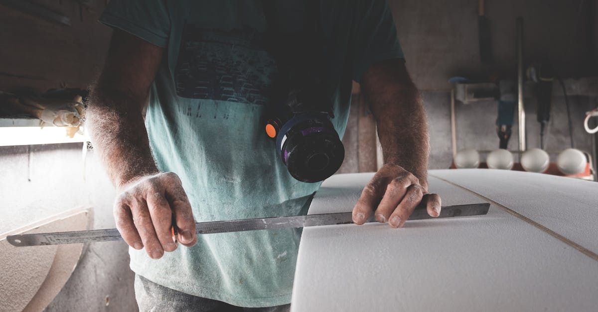 Is it possible to craft legendary items with special attributes? - Anonymous carpenter with special instrument hanging on neck using metal ruler and measuring wooden surfboard while working in professional workshop